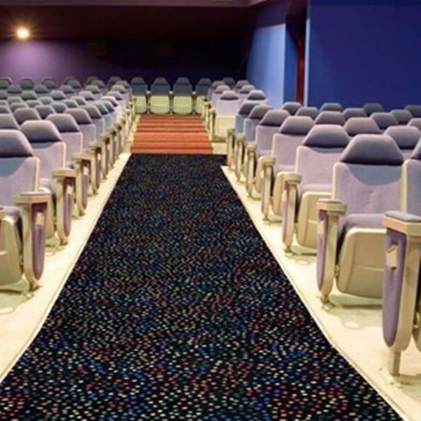 Joy Carpets Dots Aglow carpet, multi-color dot pattern on dark background, installed as aisle runner in cinema seating area