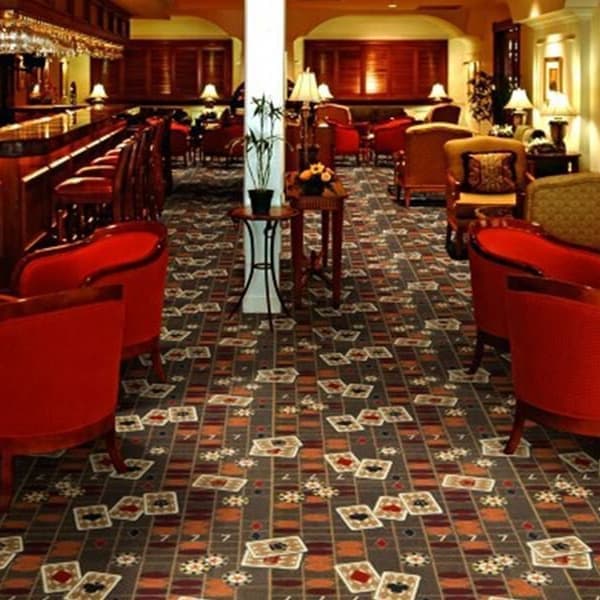 Joy Carpets Feeling Lucky Carpet, playing card pattern — lounge room with red chairs and bar, carpet covering floor