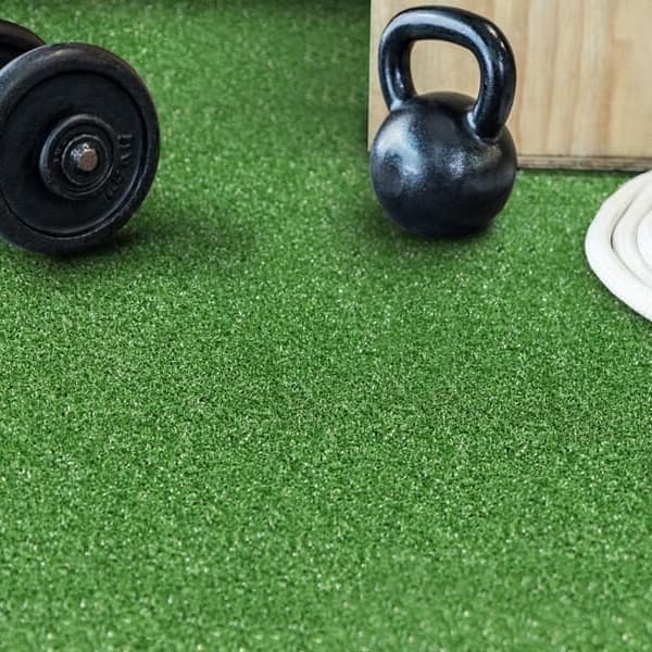 Artificial turf rolls in gym with weights.