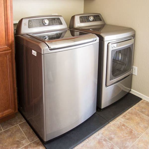 Laundry room with stainless steel washer and dryer on black recycled rubber mat over tile floor