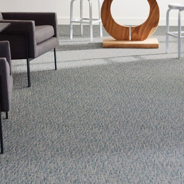 Shaw Engrain Carpet, Essential — gray textured carpet in a seating area with modern chairs and stools