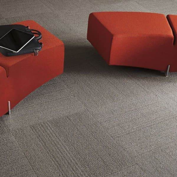 Shaw Lucky Break Carpet Tile, Luck of the Draw — modern lounge area with gray textured carpet tiles under red modular seating