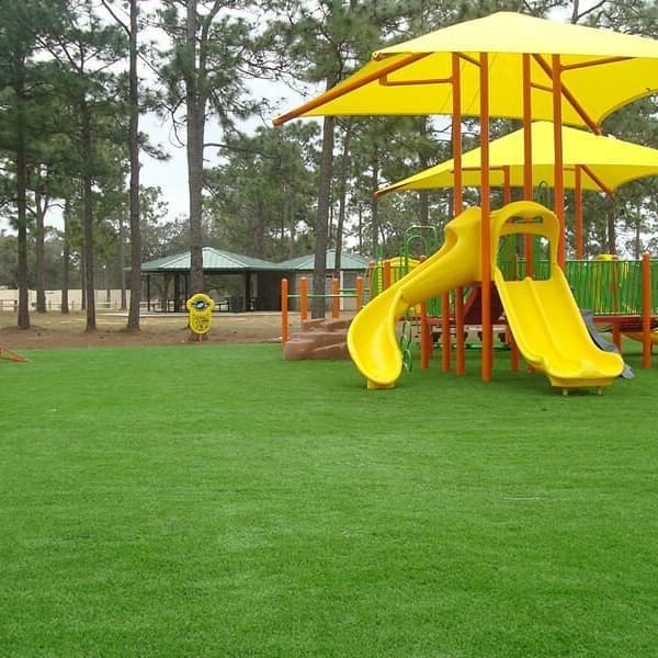 Playsafe Turf Rolls — green artificial grass covering a playground with yellow slides and climbing structures