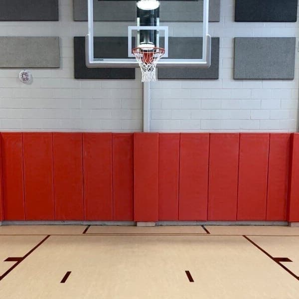 Red wall pads in gymnasium behind basketball hoop.