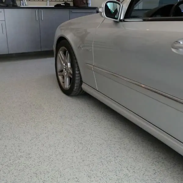 Epoxy garage flooring in garage with gray car parked.