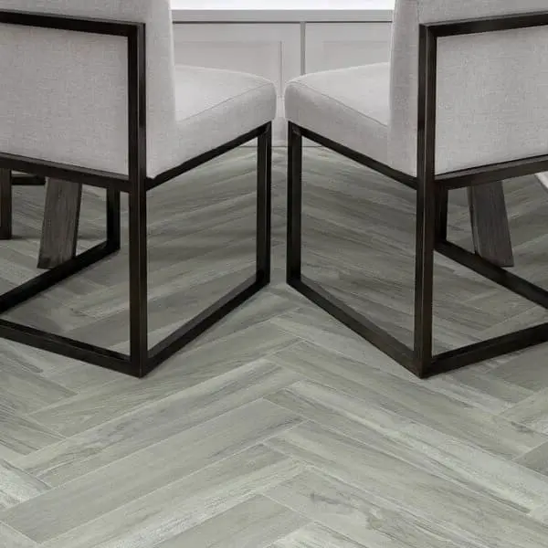 Shaw Serendipity 12' wide vinyl sheet in Andromeda — dining room floor with herringbone pattern, light gray wood grain