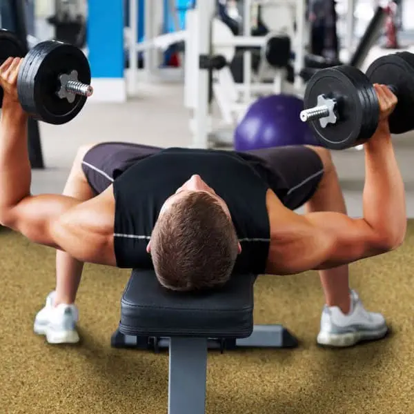 Man bench pressing in commecial gym with taupe rubber rolls.