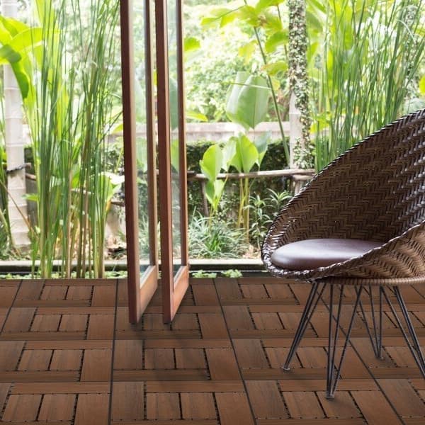 Helios Composite Deck Board Tiles in Brazilian Brown — outdoor patio with wicker chair and glass doors to garden