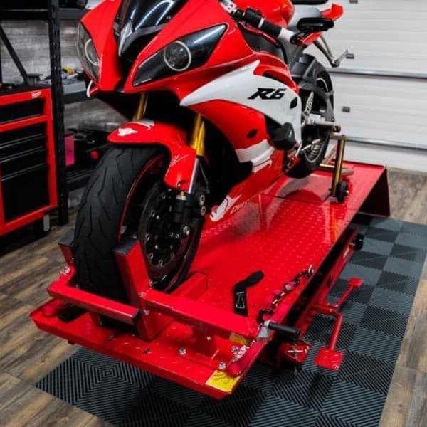 Garage with Swisstrax Ribtrax Pro Smooth Tiles in black and gray under a red motorcycle lift
