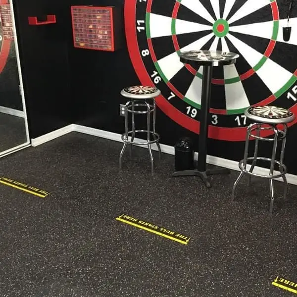 Game room with Eco-Lock Rubber Tiles in black speckled finish, featuring dartboard wall and bar stools