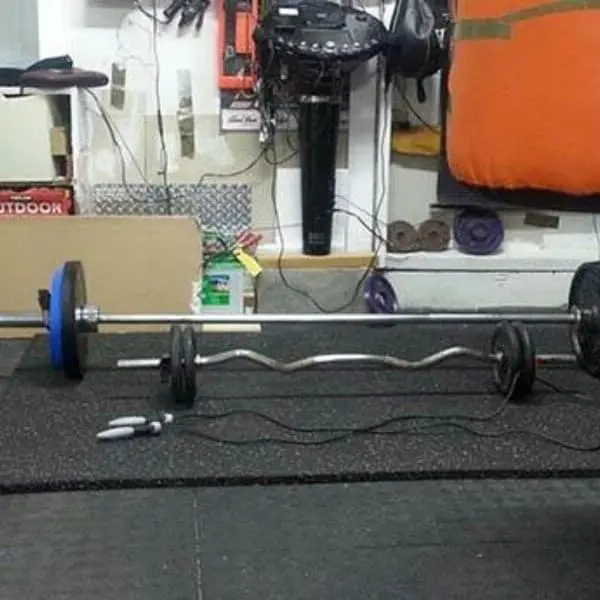 Home gym with 4' x 6' black functional fitness rubber mat under barbells and weightlifting equipment