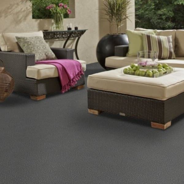 Shaw Windsurf Outdoor Carpet in Atlantic — dark gray textured carpet under patio furniture on a covered outdoor deck