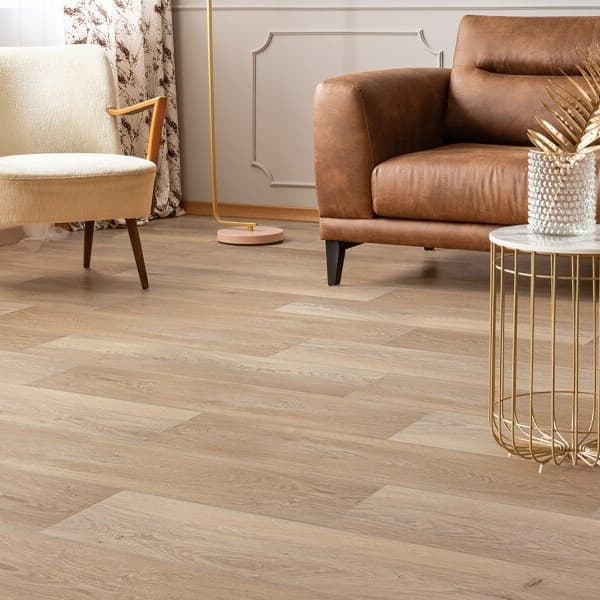 Rigid core vinyl plank flooring in a cozy living room with leather sofa, cream accent chair, and gold accent tables.