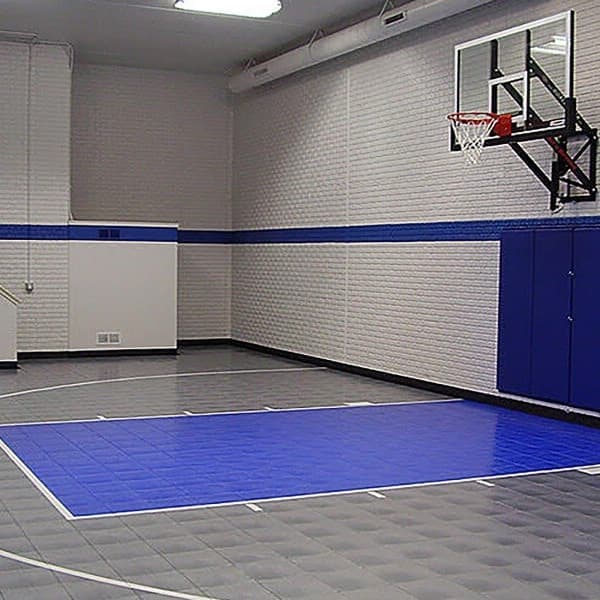Indoor basketball court with Royal Blue and Graphite indoor sports tiles, white lines, hoop, and blue padded walls