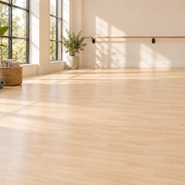 Light Oak wood-look vinyl-topped rubber roll flooring in a bright modern movement studio with a wall-mounted barre and stored mats.