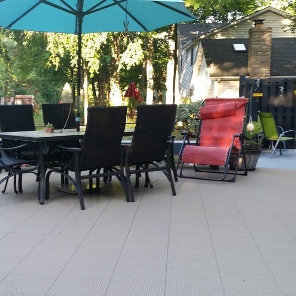 Backyard patio with ProDesign Drainage Tiles in Camel's Back, featuring outdoor dining set and lounge chairs