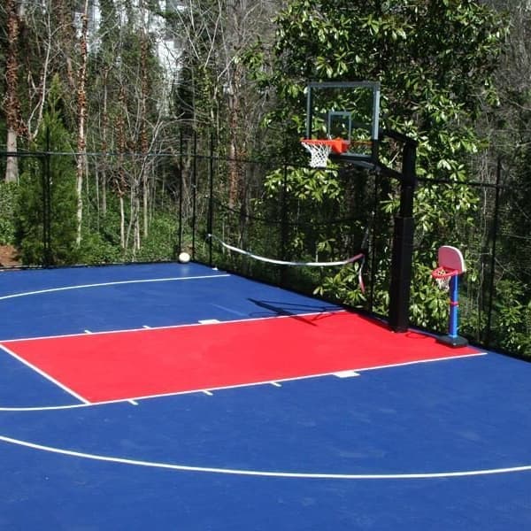 Outdoor basketball court with Shelby Blue and Victory Red polypropylene flooring, white lines, hoop, and surrounding fence