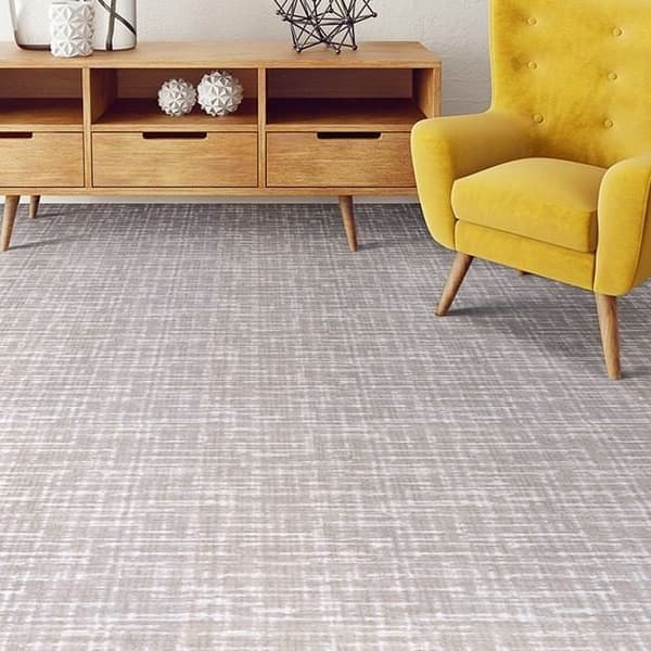 Joy Carpets Past Tense Carpet, Dove — living room with textured gray carpet under a wooden console and yellow armchair