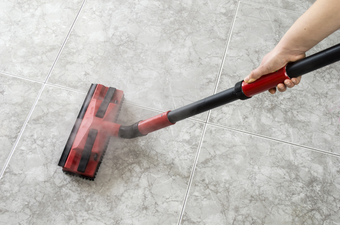 A steam cleaner cleaning tile grout.