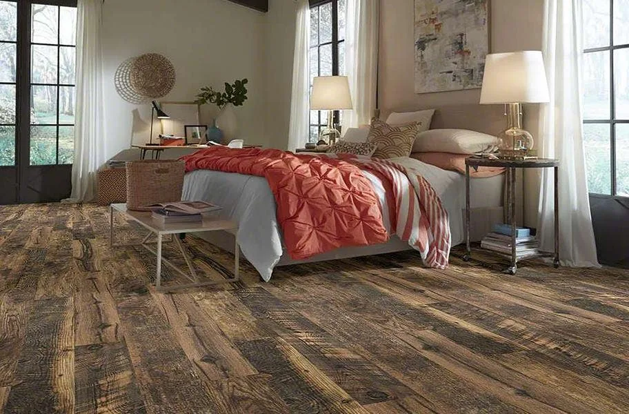 Shop Woodhaven WaterResist Laminate 12mm Woodhaven Water-Resistant Laminate in bedroom with bed, coral blankets, and night stands