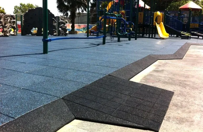 Interlocking rubber playground tiles in blue and black, creating a safe, cushioned, and ADA-compliant outdoor flooring solution for a commercial playground.