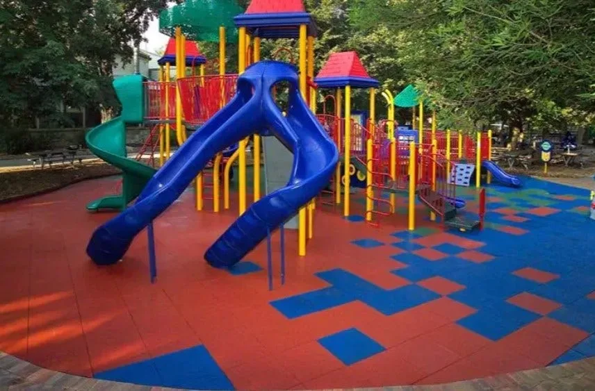 Durable rubber playground tiles in a colorful red and blue checkered pattern, creating a safe, cushioned, and vibrant flooring solution for a commercial playground.