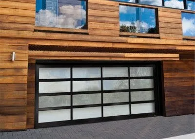 Modern aluminum and frosted glass garage door on a wood-clad home