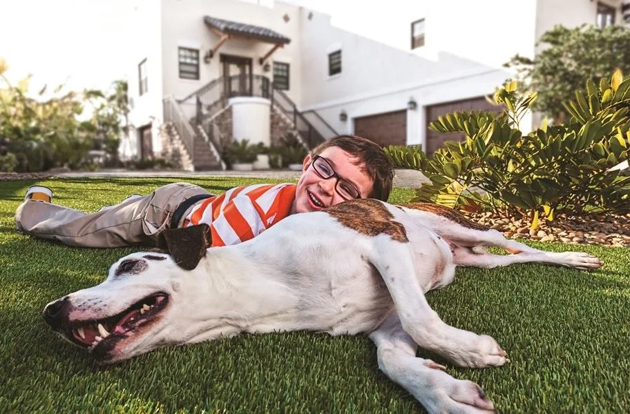 Flooring Inc turf roll in a front yard with a dog and child playing