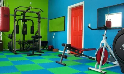 Interlocking Foam Floor Tiles Interlocking foam floor tiles in a home gym, featuring a vibrant blue and green checker pattern that provides a cushioned and anti-fatigue workout surface.