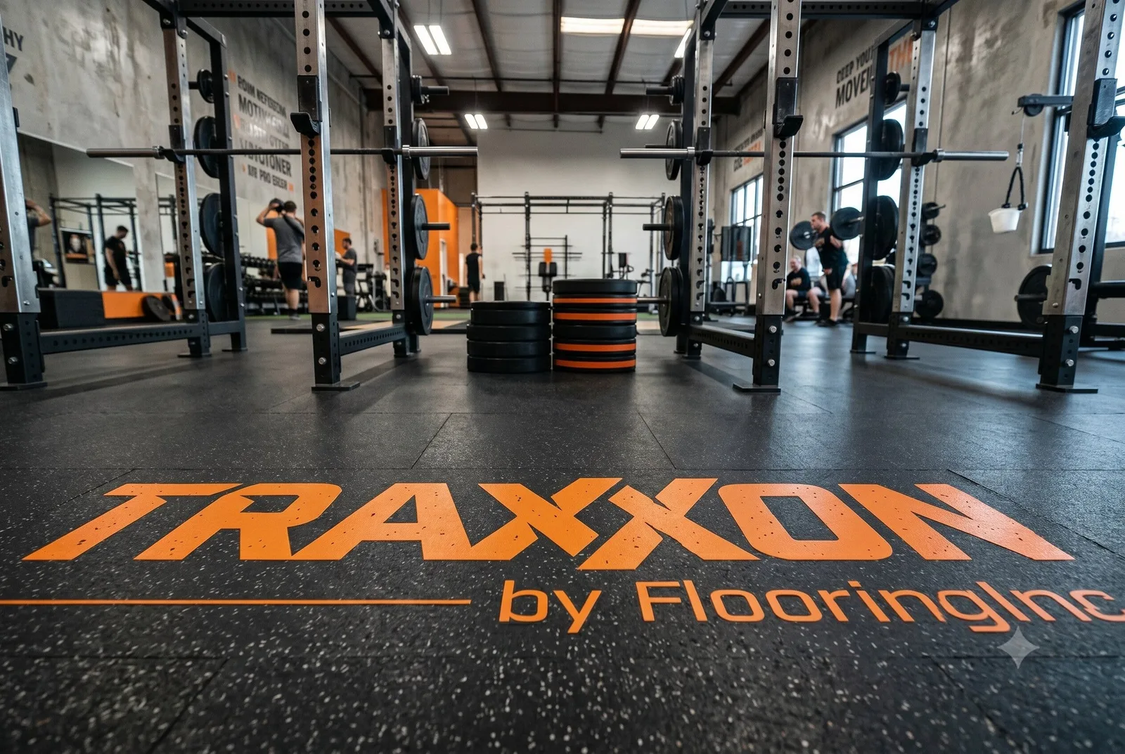 This image shows the Traxxon rubber flooring logo over black rubber flooring in a weight room.