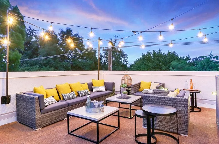 Rooftop lounge with wicker sofas and string lights on interlocking deck top roof tiles