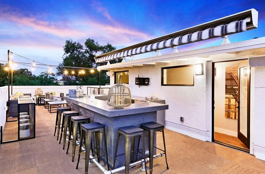 Rooftop bar with stools on tan interlocking deck top roof tiles at sunset
