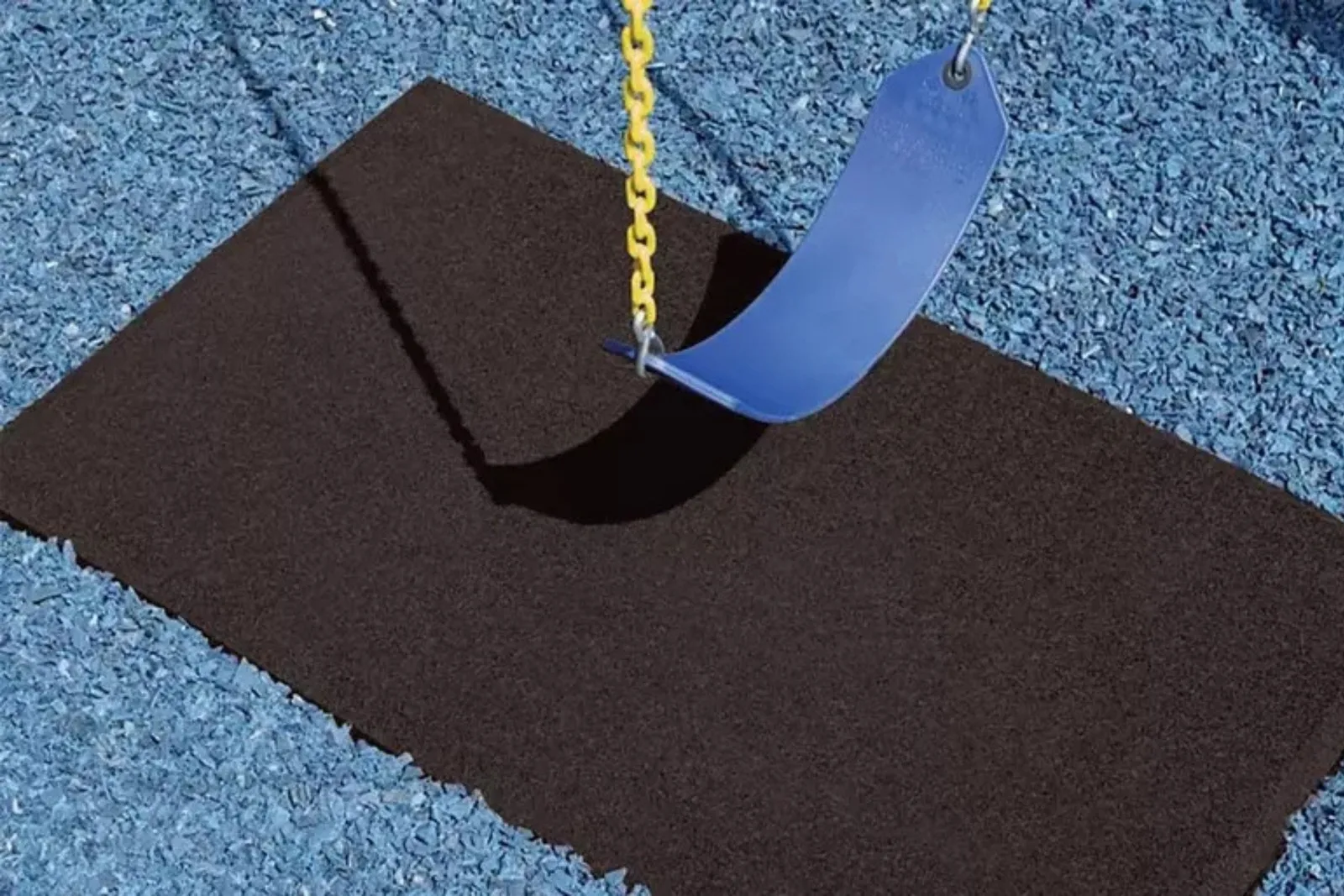 Durable black rubber playground mat Close-up of a blue swing over a durable black rubber playground mat on blue rubber mulch, providing essential fall protection.