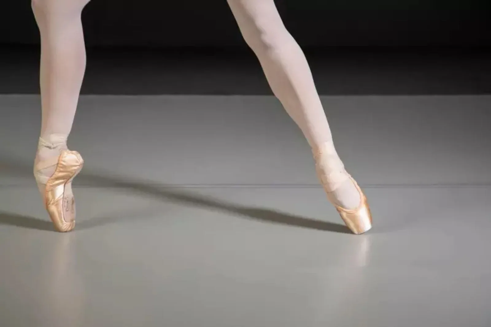 Durable gray Marley dance flooring Close-up of a ballerina en pointe on durable gray Marley dance flooring, showcasing a smooth and specialized surface for dance.