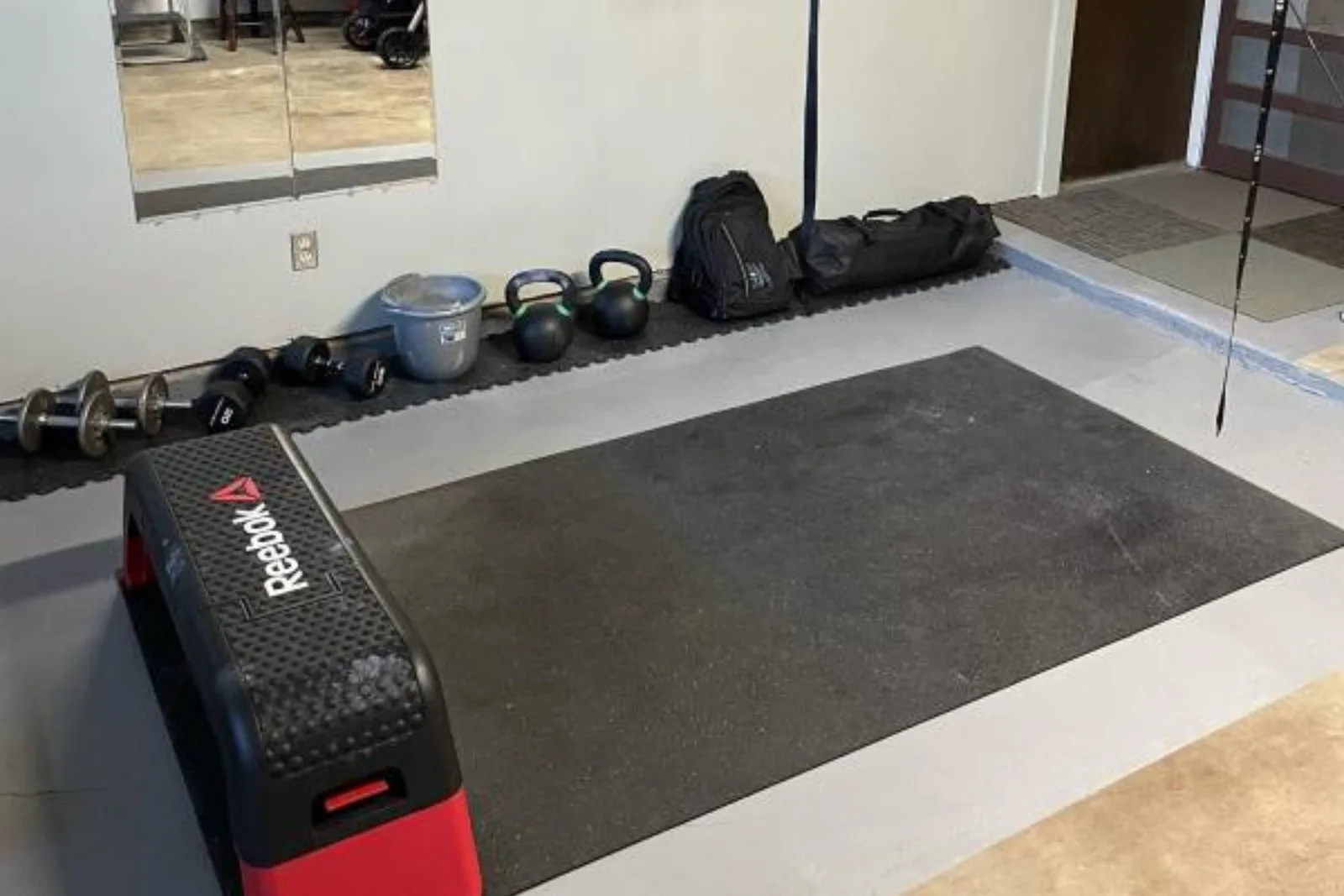 Reebok step and dumbbells on a 1/4-inch tough rubber mat in a home gym