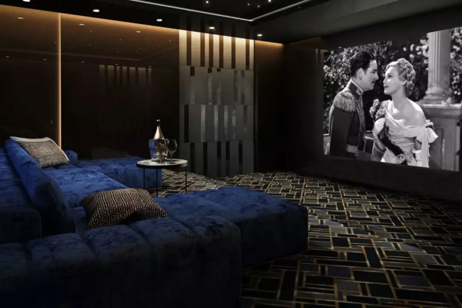 Modern Home Theater System Setup Luxury home theater with deep blue velvet sectional seating, Art Deco patterned carpet, and a large projection screen showing a classic film.