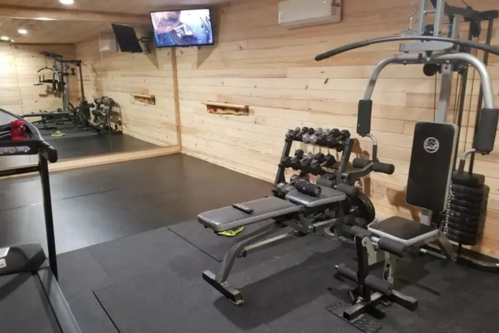 Garage home gym with a bench and dumbbell rack on 4 by 6 foot rubber gym mats