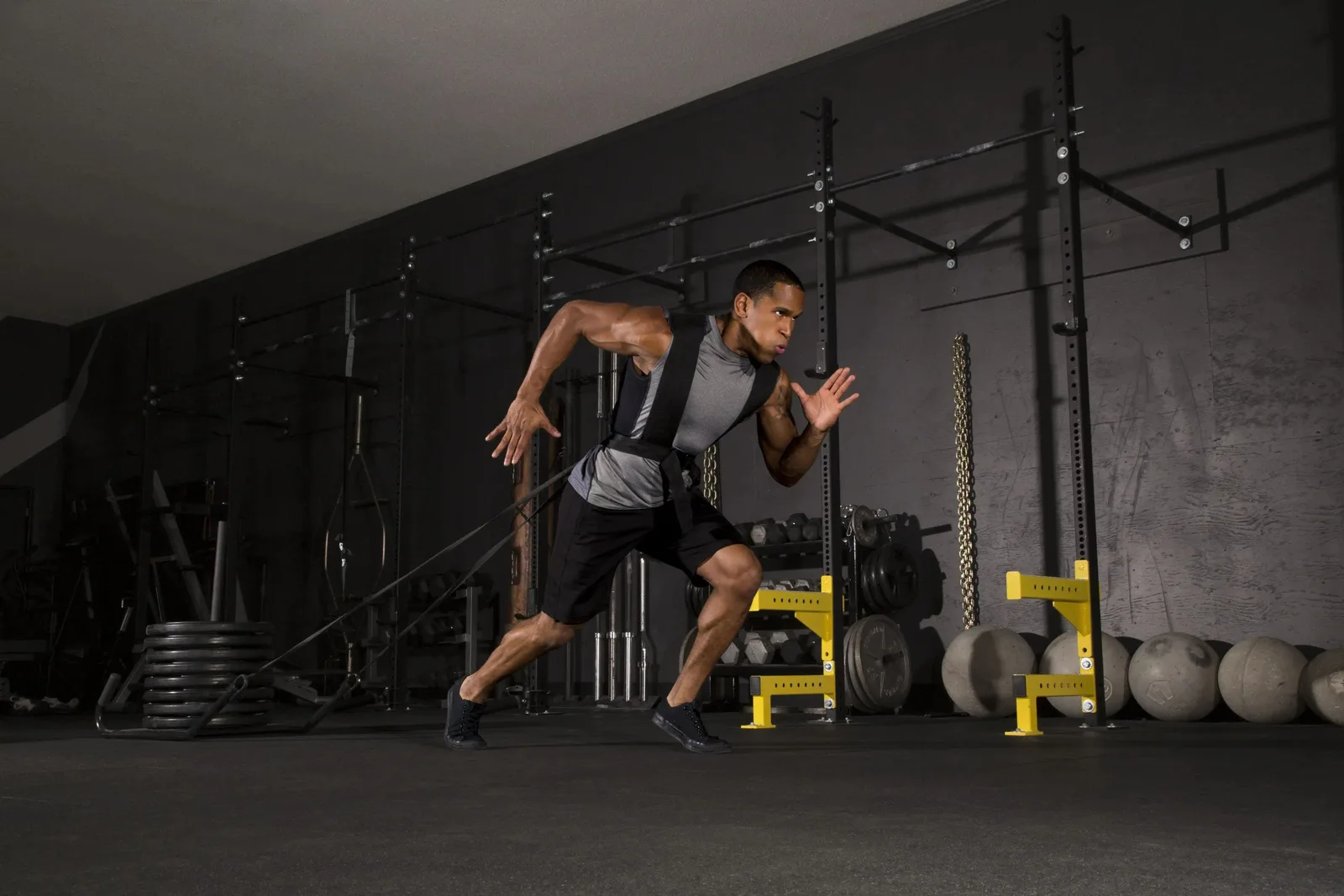 Athlete doing a sled-pull sprint on black rubber gym flooring