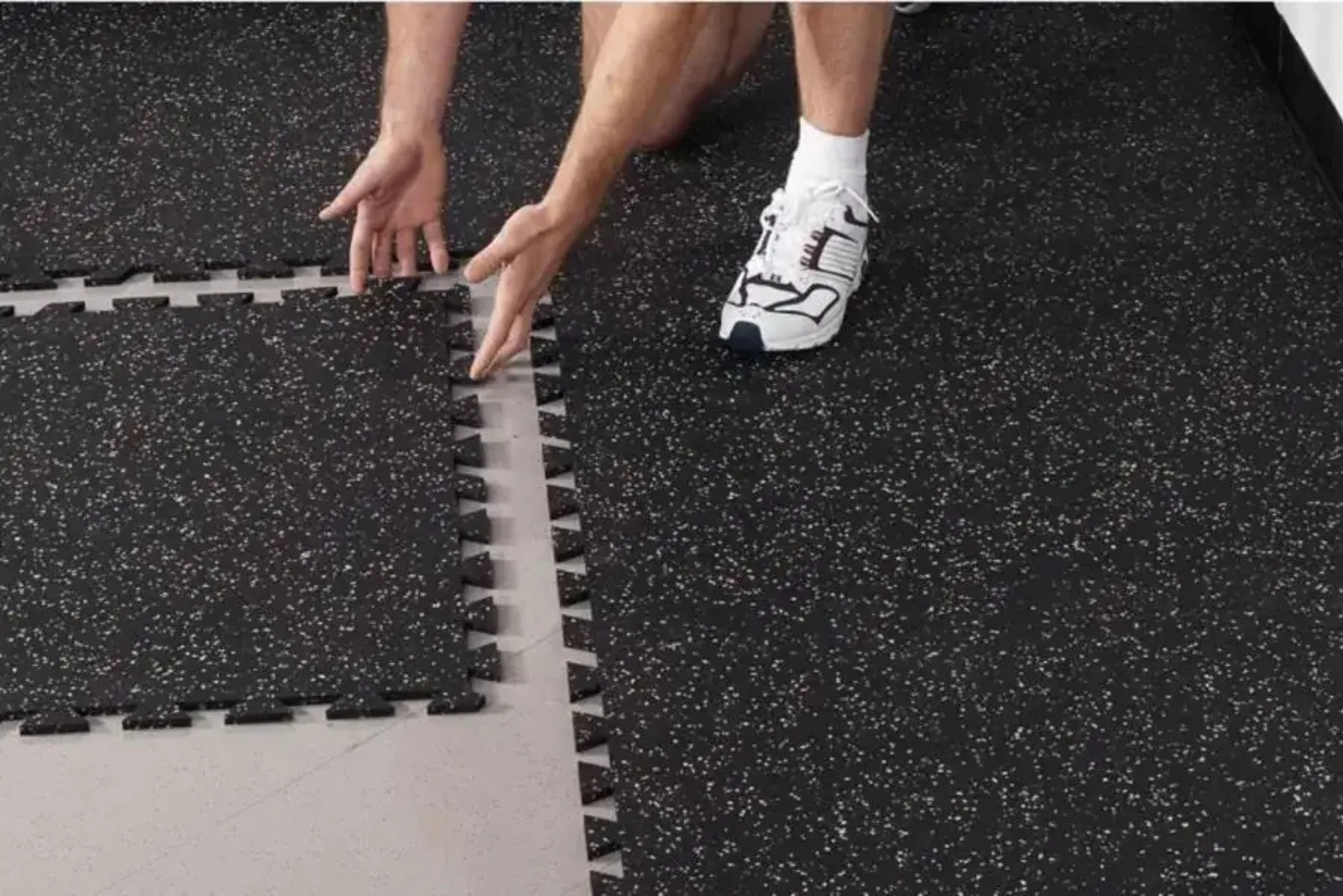 Hands fitting interlocking rubber gym tiles together