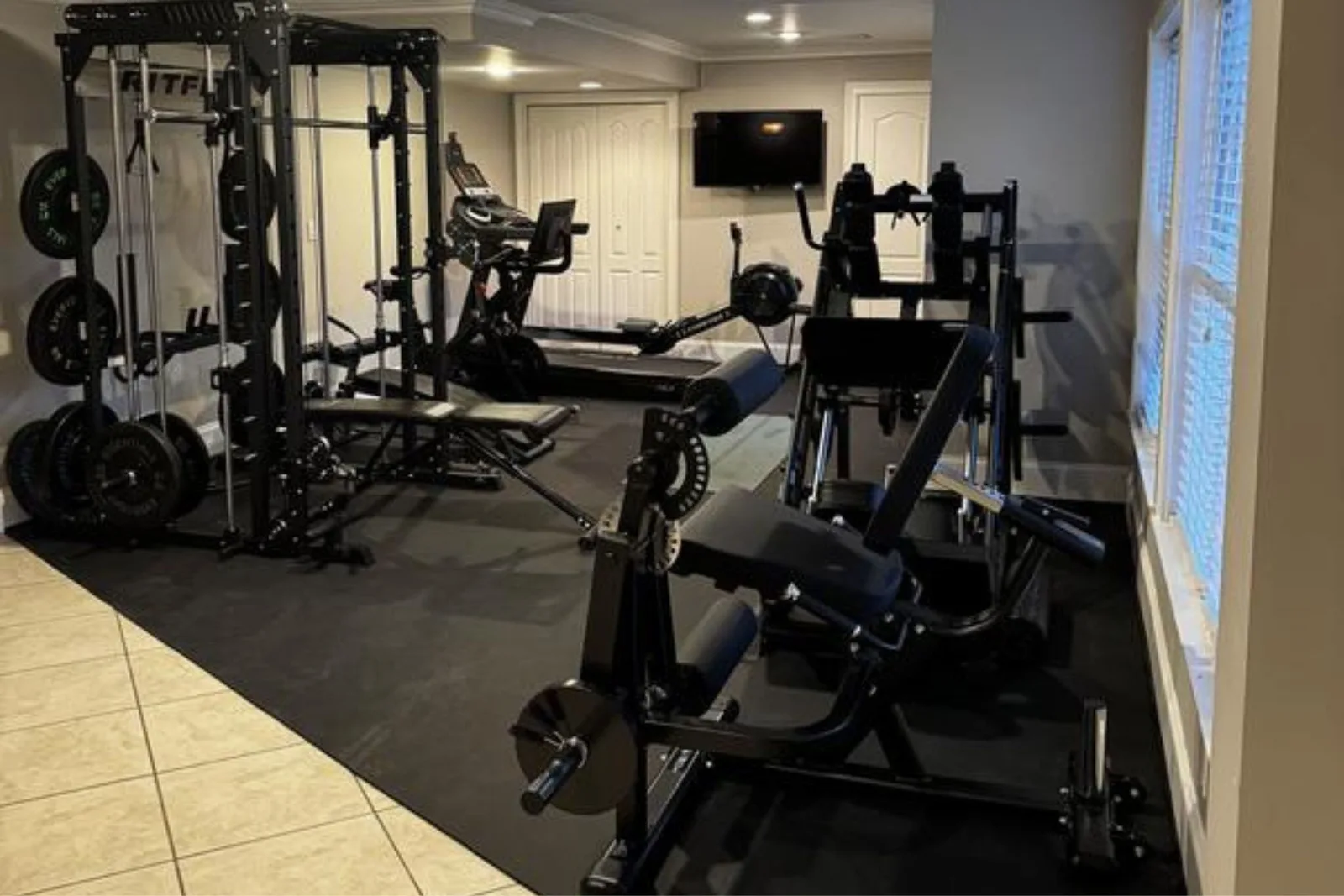 Home gym with a power rack and machines on custom-cut rubber rolls