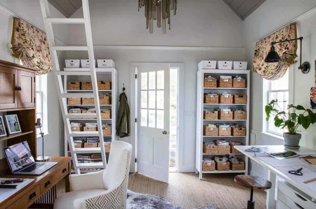 Modern she shed office with white walls, a rolling ladder, basket shelves and a desk