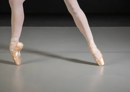 Ballet dancer en pointe on a gray marley dance floor