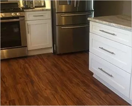 Kitchen with white cabinets on dark wood-look COREtec Plus vinyl planks