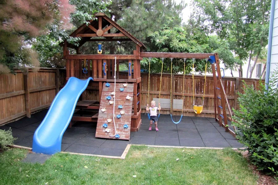 Black playground tiles used under a playset in a residential backyard