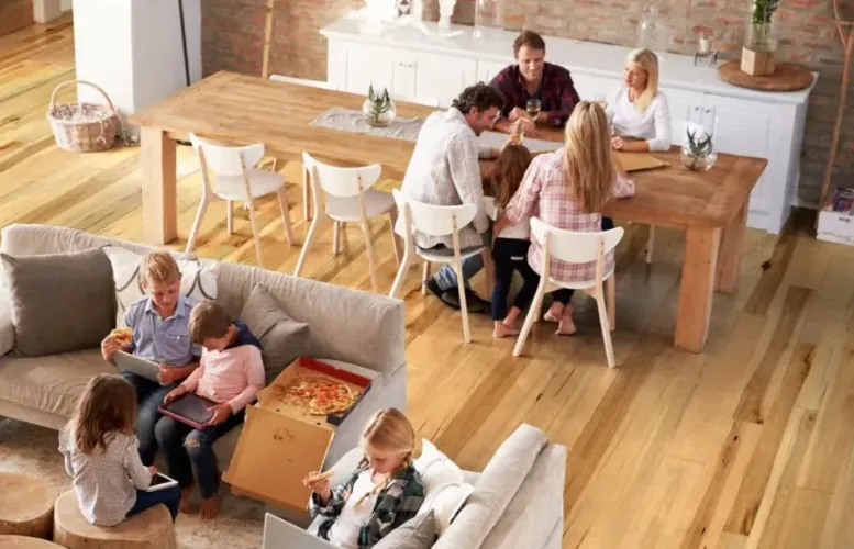 Happy family enjoying a meal in a large open-concept living space with durable light wood-look vinyl plank flooring, a low-maintenance and water-resistant flooring solution.