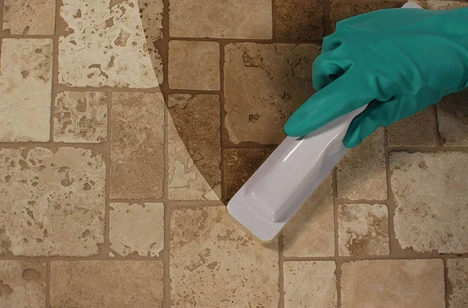 Gloved hand applying sealer to travertine tile with an applicator pad