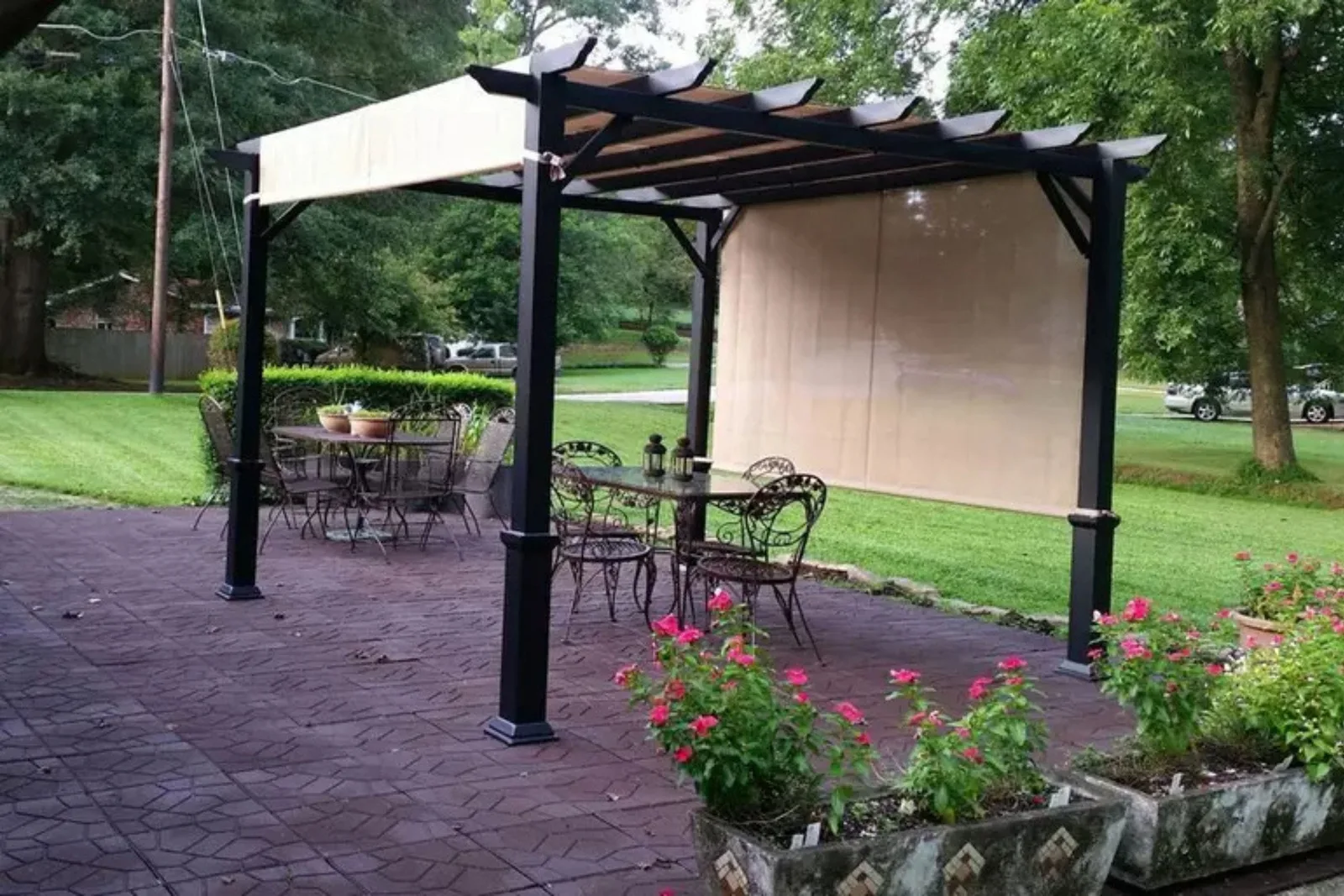 Flagstone rubber patio pavers in a dark red color create a comfortable and slip-resistant outdoor flooring solution under a pergola with patio furniture.