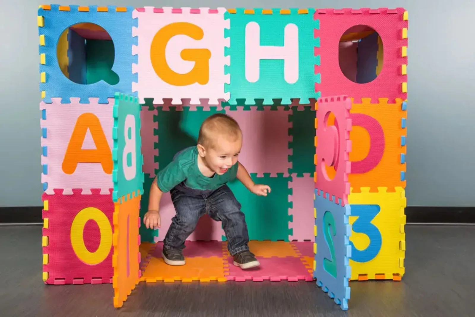 ABC foam floor tiles in a vibrant, multicolored design, used to create an interactive play cube for a toddler, teaching letters and numbers while providing a safe play mat surface.