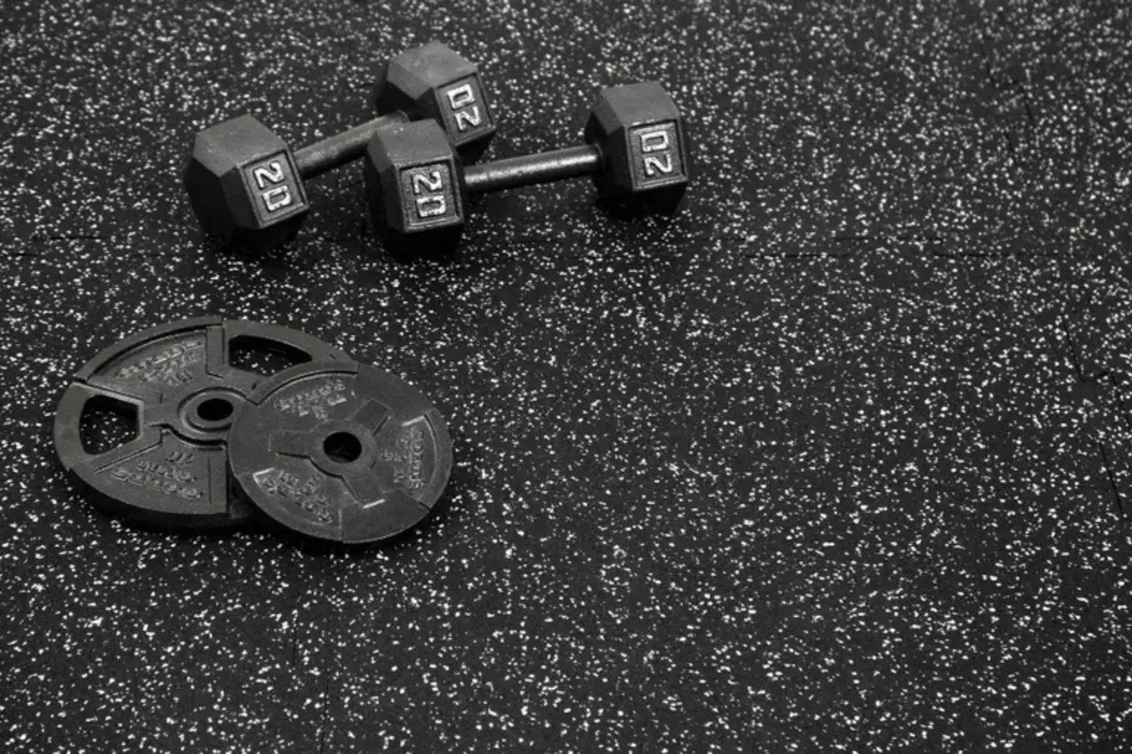 Close-up of durable black speckled rubber gym flooring, a protective and high-performance solution for weight rooms and fitness centers.Close-up of durable black speckled rubber gym flooring, a protective and high-performance solution for weight rooms and