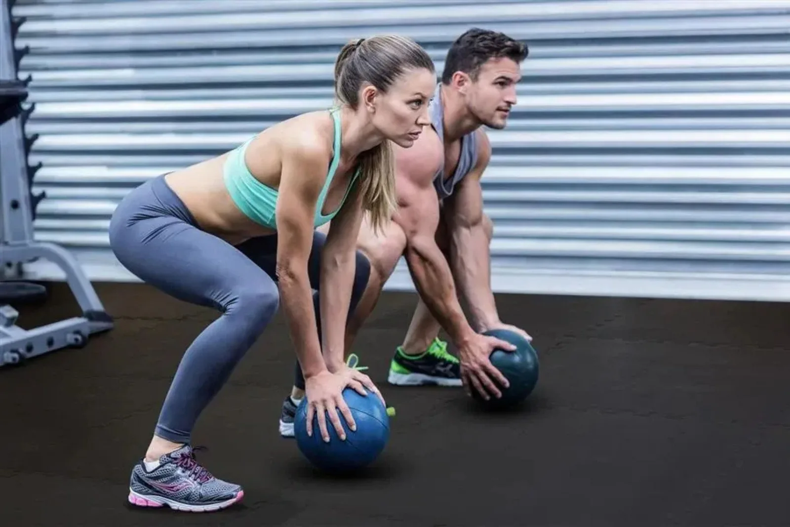 Two people working out on durable black interlocking gym floor tiles, a high-performance and protective flooring solution for a gym or athletic space.